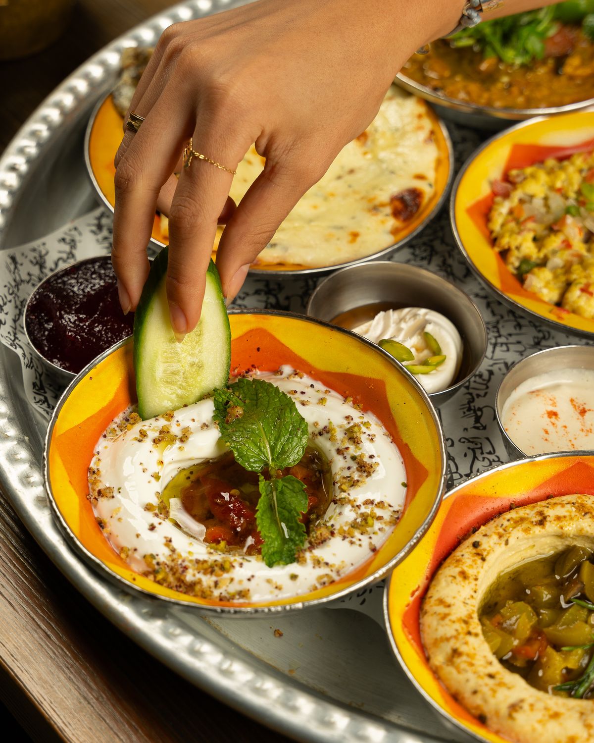 A cucumber being dipped into a creamy spread