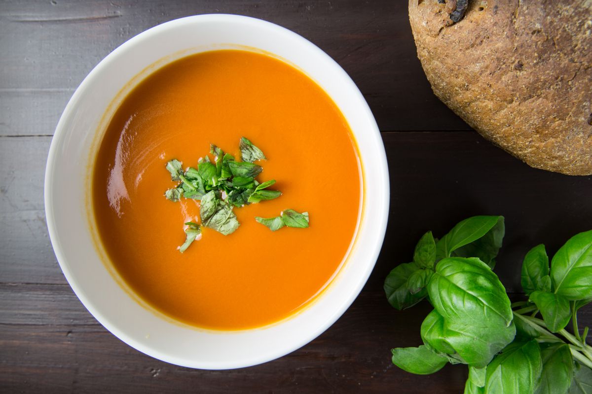 A bowl of vegetable soup with herbs and bread